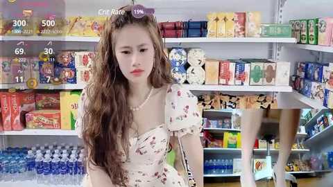 Media: Video of an Asian woman with long brown hair, wearing a white floral dress, standing in a brightly lit convenience store.