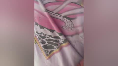 Media: A video of a woman wearing a colorful, patterned shirt featuring a graphic design of a mermaid and abstract waves. The shirt is predominantly white with pink, black, and yellow accents.