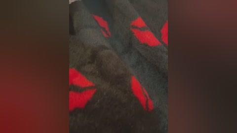 Media: Video of a dark fabric with scattered bright red lips-shaped designs, creating a playful and mysterious pattern. The fabric texture is soft and fuzzy, likely wool or fleece.