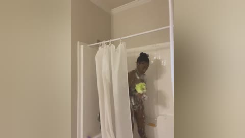 Media: A video of a young, slim, nude Black woman with dark skin, small breasts, and a slender build, standing in a beige-tiled shower with white curtain, holding a green bottle.