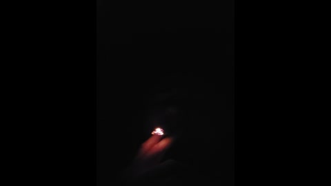 Media: A video of a single lit match with a faint red glow, set against a pitch-black background. The image captures the brief moment of ignition, emphasizing the stark contrast between light and darkness.