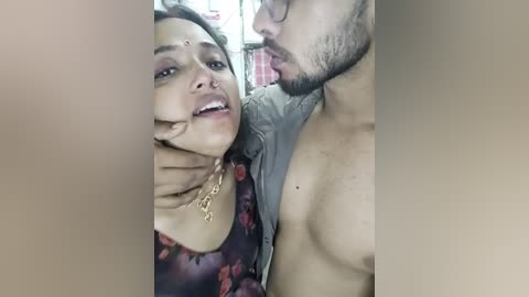 Media: Video of a South Asian woman with medium skin tone, wearing a floral dress, and a man with medium skin tone, shirtless, kissing her neck.