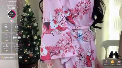 Media: A video of a woman in a pink kimono with cherry blossom print, standing next to a lit Christmas tree.