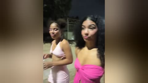 Media: Video of two women in a night club; one in a pink dress, the other in a bright pink off-shoulder dress, both smiling.