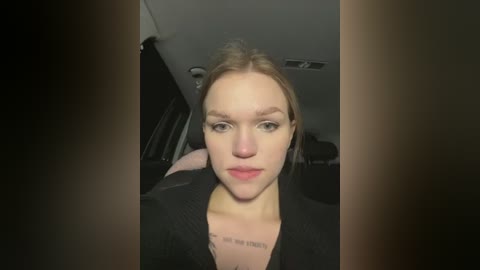 Media: Video of a young, fair-skinned woman with light brown hair, wearing a black top, sitting in a car with dark surroundings.