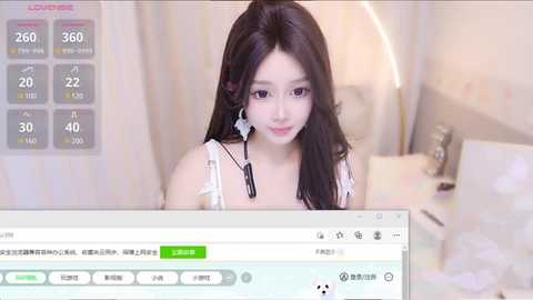 Media: A video of a young Asian woman with long black hair, wearing a white dress, sitting in front of a computer screen. The screen displays a live stream with her image.