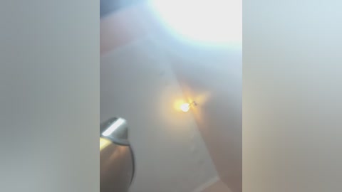 Media: A video captures a close-up of a white, semi-transparent glass door with a small, glowing light bulb on the left side, casting a warm, soft glow. The image is slightly blurred, giving it a dreamy, ethereal feel.