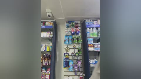 Media: Video of a pharmacy aisle with two shelves displaying various medications, vitamins, and personal care products, including toothbrushes and mouthwash. The shelves are organized neatly, with blue and white signage.