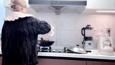 Media: Video of a woman in a dark, fluffy robe, cooking on a white countertop with a stove and blender, white tiles in the background, stainless steel appliances, and a cozy, domestic setting.