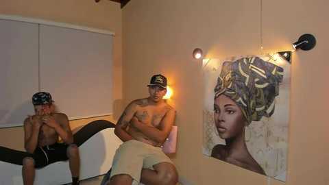 Media: Video of three shirtless Black men sitting on a white couch in a dimly-lit room with beige walls and a large painting of a woman with an elaborate head wrap.