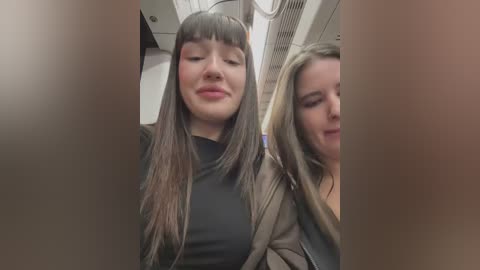 Media: Video of two young women with long hair, one in a black top and the other in a green jacket, smiling in a subway car.