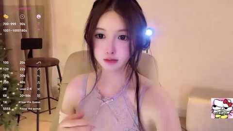 Media: Video of an Asian woman with pale skin and long black hair, wearing a white lace top, sitting on a beige chair, with a video overlay showing streaming statistics.