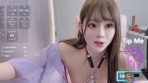 Media: Video of a young Asian woman with straight, long brown hair, wearing a pastel pink top, taken indoors with a virtual reality headset, displaying a \"Tip Me\" prompt.