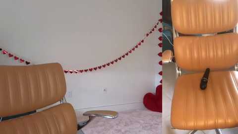 Media: Video of a minimalist, modern room with beige leather chairs and white walls adorned with red heart garlands and a red heart-shaped pillow.