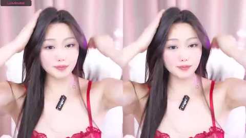 Media: Video of an East Asian woman with long black hair, fair skin, and light makeup, wearing a red lace bra, adjusting her hair in a bedroom with white bedding and pink curtains.