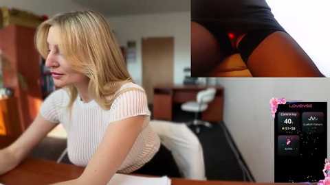 Media: A video featuring a blonde woman in a white top, leaning on a desk in a modern office. Inset: close-up of black panties with a red thong.