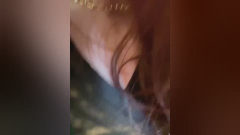 Media: A blurred video captures the profile of a woman with long brown hair, wearing a golden necklace, against a dark background.