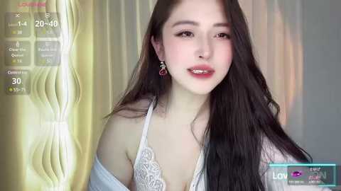 Media: Video of an East Asian woman with long black hair, fair skin, and red lipstick, wearing a white lace bra, against a blurred yellow and white background.