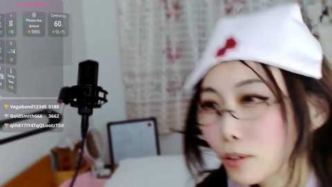 Media: Video of an East Asian woman in a nurse outfit, with a white hat and red cross, singing into a black microphone, with a TV screen displaying streaming statistics in the background.