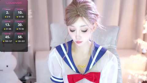 Media: Video of a young, fair-skinned Asian woman in a Sailor Moon cosplay outfit, with soft, pastel-toned background, showing her in a relaxed, seated position.