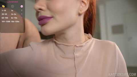 Media: A close-up video of a fair-skinned woman with red hair, wearing a sheer pink top, captured from the neck up. The background is blurry, with a smartphone app interface showing skin tone and lighting details.