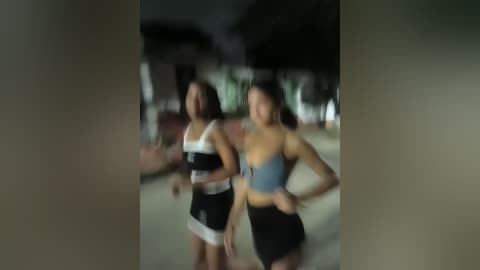 Media: Video of two young women in black and white lingerie, standing outdoors at night. Background is blurred, showing trees and buildings.