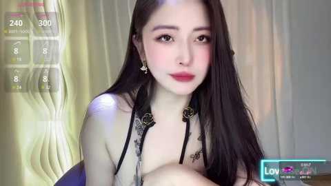 Media: Video of a fair-skinned East Asian woman with long black hair, wearing a black lace bra, posing in front of a yellow curtain, with a \"LIVE\" screen overlay.