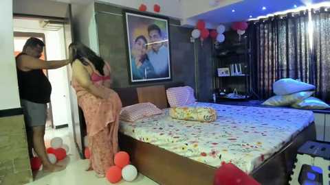 Media: A video of a modern bedroom with a man and woman in a passionate embrace, surrounded by red balloons, white curtains, and a framed family photo on the wall.