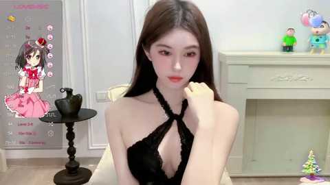 Media: Video of a young, slender Asian woman with long, straight black hair and fair skin, wearing a black halter top, sitting indoors near a white table and chair. Background includes a poster and a colorful, cartoonish toy.