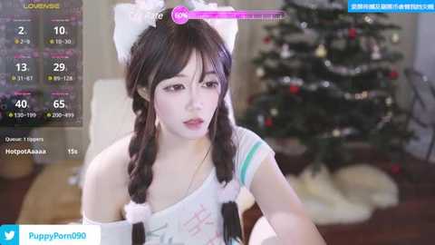 Media: A video of an Asian woman with long black hair, wearing a white off-shoulder top with cat ears, in a festive room with a decorated Christmas tree.