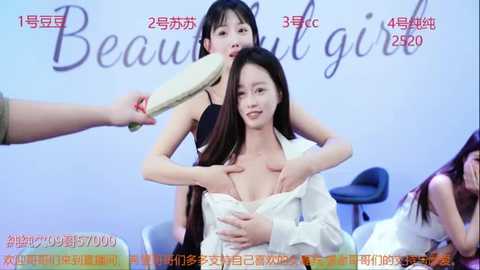 Media: A video of an East Asian woman with long dark hair, partially undressed in a white shirt, being held by a female presenter, set against a light blue backdrop with \"Beautiful Girl\" text.