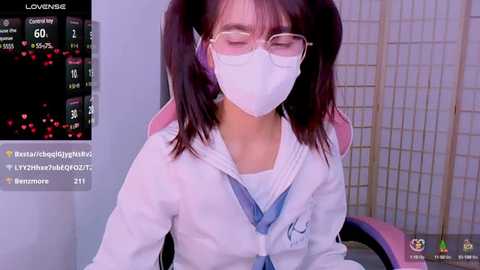 Media: Video of an East Asian woman with pigtails, wearing a white lab coat, mask, and glasses, sitting in a gaming chair. Background shows a live streaming screen with viewers' comments and stats.