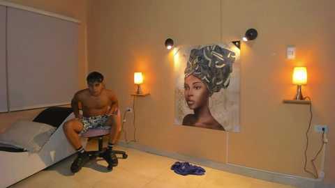 Media: Video of a shirtless man in shorts sitting on a stool in a minimalist, beige-walled room with a large portrait of a woman with a head wrap and two wall lamps.