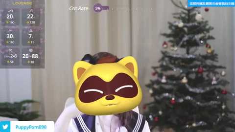 Media: Video of a person wearing a raccoon mask with yellow fur, brown mask, and closed eyes, standing in front of a decorated Christmas tree with ornaments, in a cozy, festive indoor setting.