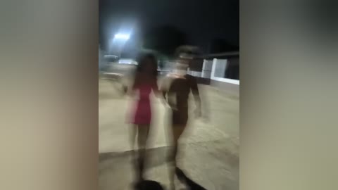 Media: A blurry video of a nighttime street scene shows a young woman in a pink dress and a man in a black shirt walking together. The background features a dimly lit, deserted road with parked cars and a distant building.