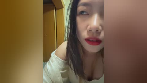 Media: Video of an Asian woman with light skin, dark hair, and red lipstick, leaning forward, partially obscured by a wooden door frame.