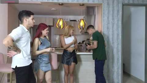 Media: Video of four young adults in a modern kitchen. Two men and two women, one in a white shirt, one in a green shirt, and two in casual clothes.