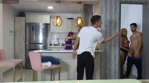 Media: Video of a modern kitchen with a shirtless man in white pants, a woman in a purple dress, and a naked man in blue underwear.