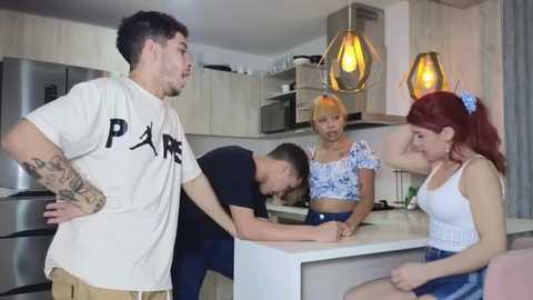 Media: Video of four people in a modern kitchen: two men, a woman with a tattoo, and a blonde girl with a ponytail.