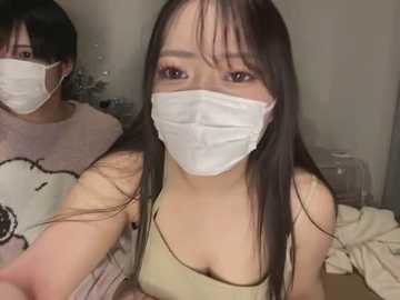 Media: Video of an Asian woman with long black hair, wearing a white mask, beige top, and black sweatpants. Background shows a messy bed and a white cage.