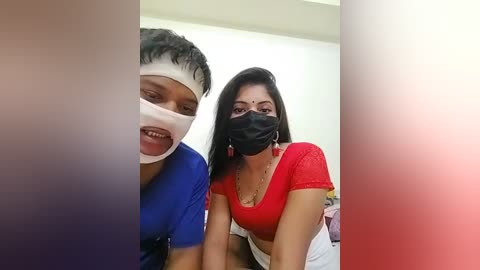 Media: Video of two South Asian women wearing surgical masks and blue scrubs, one with a bandaged head, smiling. Background is a sterile medical setting.