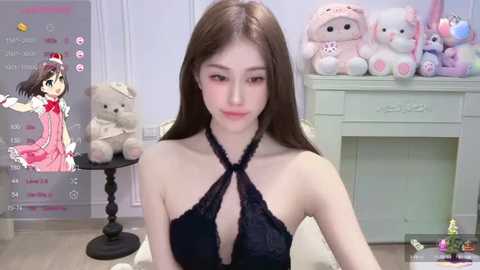 Media: Video of a young Asian woman with long brown hair, wearing a black halter top, seated in a pastel-colored room adorned with plush toys and a teddy bear.