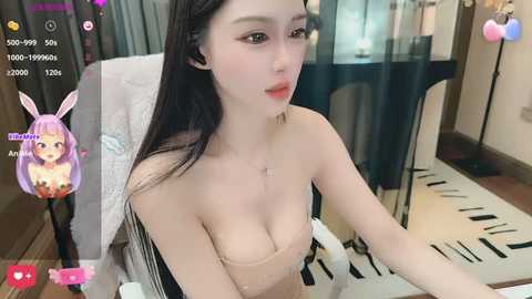 Media: Video of a young East Asian woman with long black hair, fair skin, and large breasts, wearing a strapless top, sitting in a modern room.