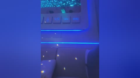 Media: A video of a dimly lit, futuristic interior featuring sleek, white furniture with blue LED strip lighting. The room's ambiance is calm and modern, with a minimalist design.