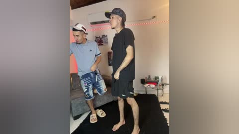 Video of two men in casual attire, standing on a black mat in a modern living room with a TV, couch, and wall art.