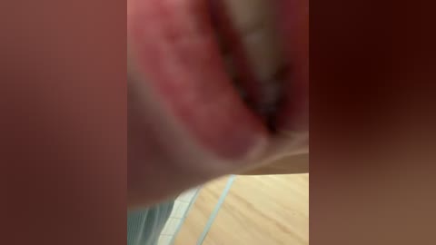 Video of a close-up of a human mouth with visible teeth and tongue, set against a blurred background. The image is slightly out of focus, with a warm, reddish-brown tone dominating the scene.