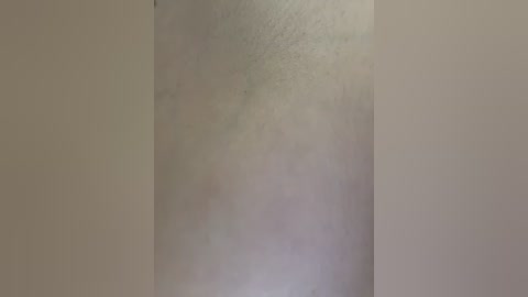 Video of a close-up, pale human arm with light skin tone, showing natural skin texture and slight blemishes, set against a plain beige background, emphasizing the natural human form.