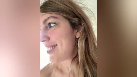 Video of a Caucasian woman with fair skin and light brown hair, smiling, in profile against a gradient background transitioning from light to dark brown.