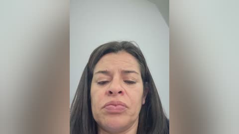 A video of a woman with long, dark hair, fair skin, and a pouty expression, captured against a plain white background.