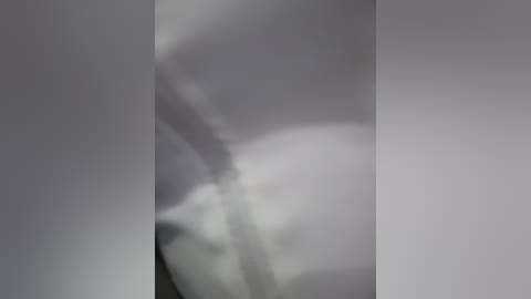 Blurry video of a person's face, possibly in profile, with indistinct features and a soft, greyish color palette, suggesting a low-light setting or a filter effect.